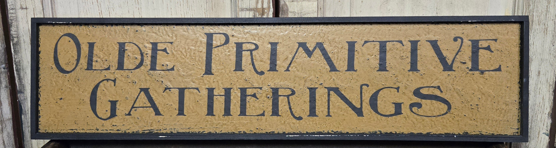 Wooden sign with 'Olde Primitive Gatherings' text on a wooden background