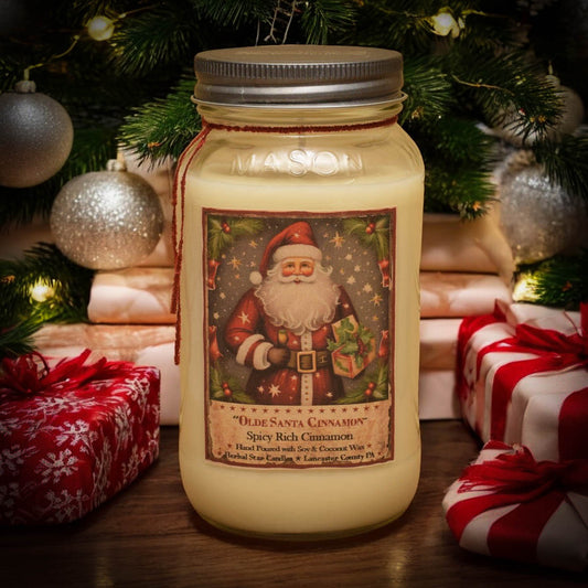 A 24 oz mason jar candle with a 'Santa Cinnamon' label, surrounded by holiday decorations including presents and a Christmas tree in the background.