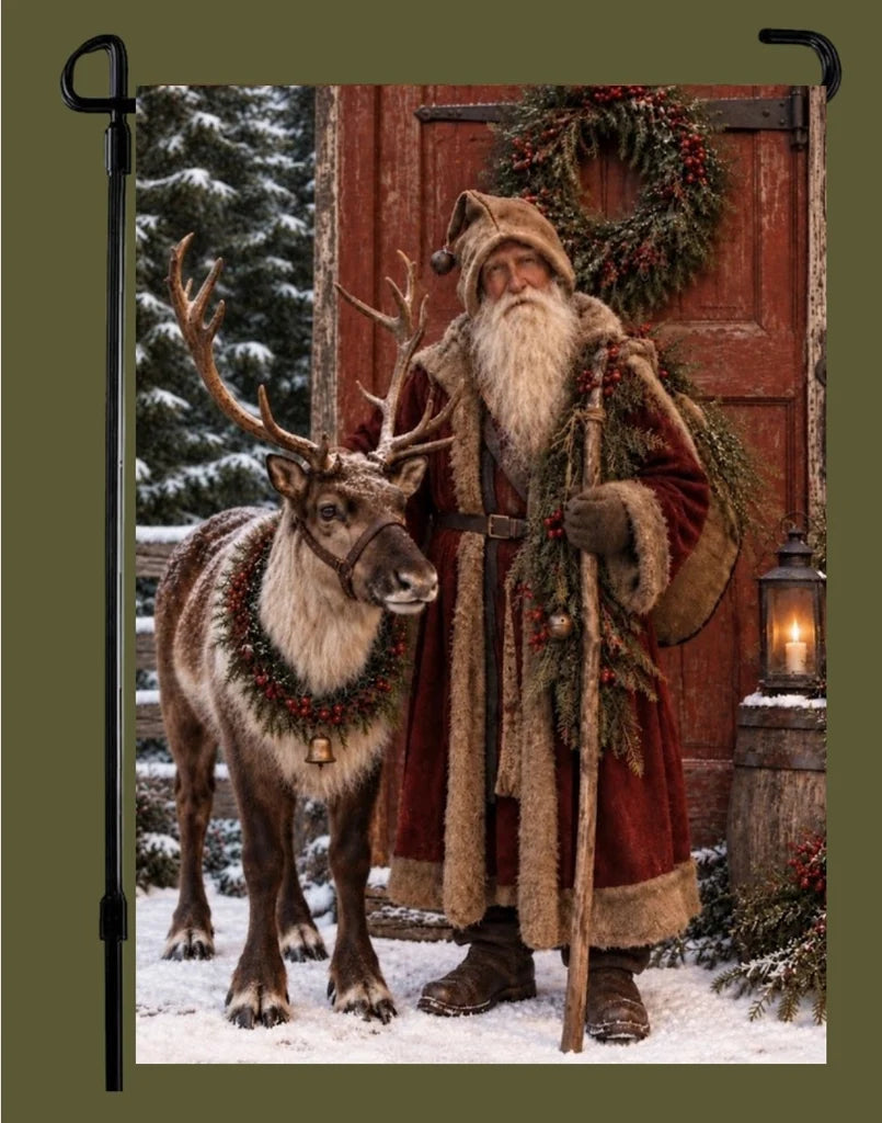 Garden flag featuring an old-world Santa in a fur-trimmed red robe beside a reindeer, with a snowy evergreen, wreath, and glowing lantern.