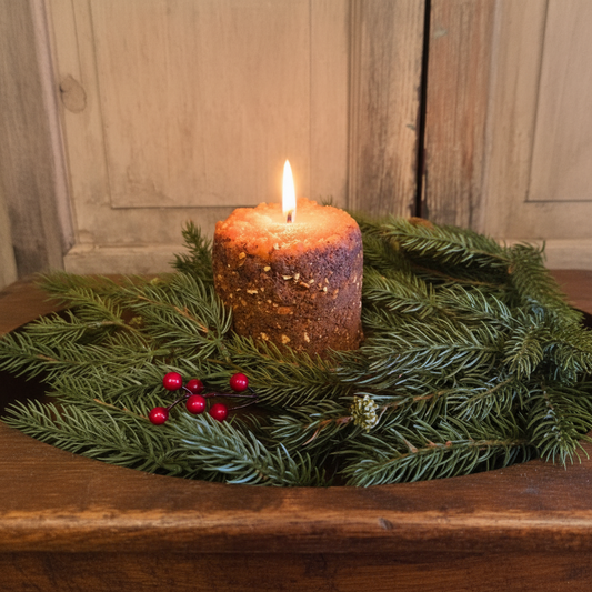 Candle in a wooden holder with greenery on a rustic wooden surface
