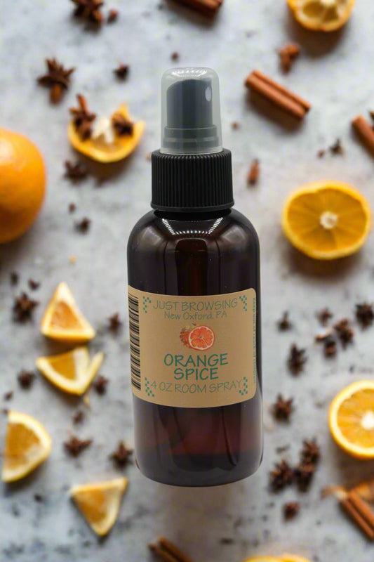 A 4oz bottle of Orange Spice Room Spray with a mist spray top, primarily brown in color with a label that includes the product name and a barcode.