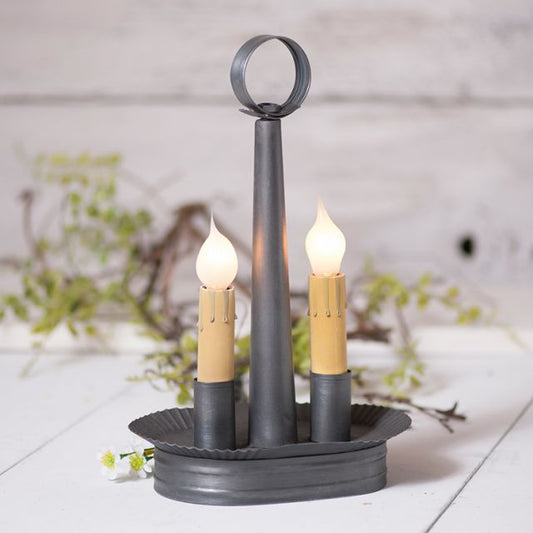 Decorative candle holder with two lit candles on a wooden surface.