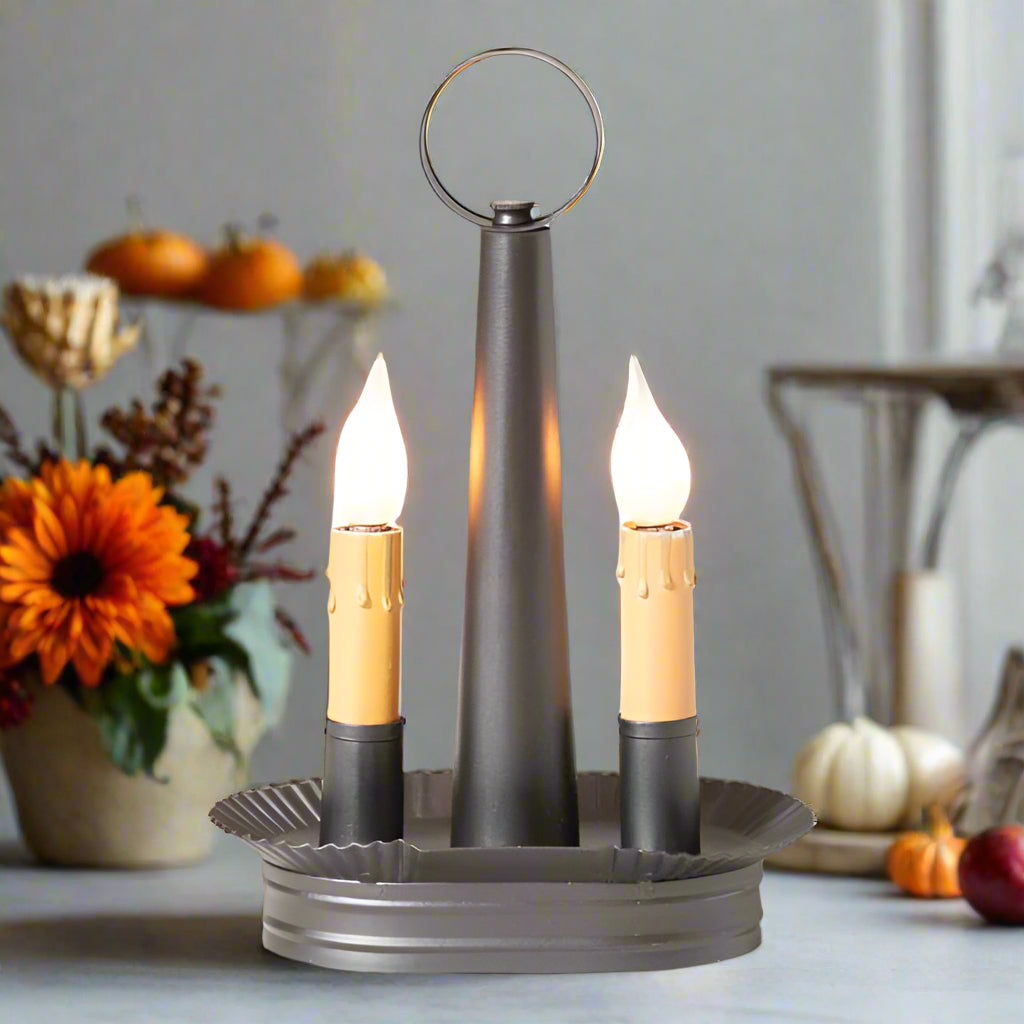 An oval-shaped double accent light in smokey black finish with two bulb sockets, a metal construction, and a circular ring at the top.