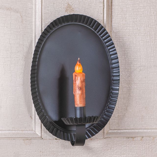 Decorative wall sconce with a candle-like light on a textured wall.