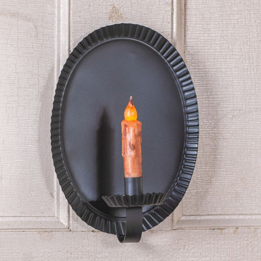 Decorative wall sconce with a candle-like light on a textured wall.