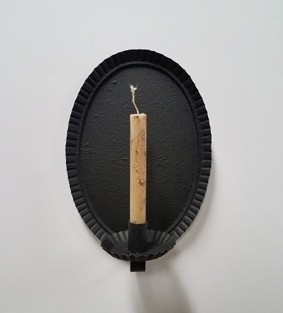 A black oval-shaped metal sconce with a textured finish, designed to hold a battery taper candle.