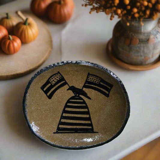 Decorative plate with black abstract design on a wooden surface
