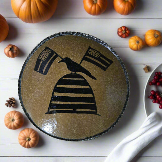 Round stoneware plate with a crow, flag and bee skep motif