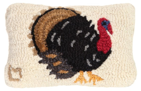 A rectangular hooked wool pillow with a turkey design, featuring a combination of beige, brown, and red colors, with a velveteen backing.
