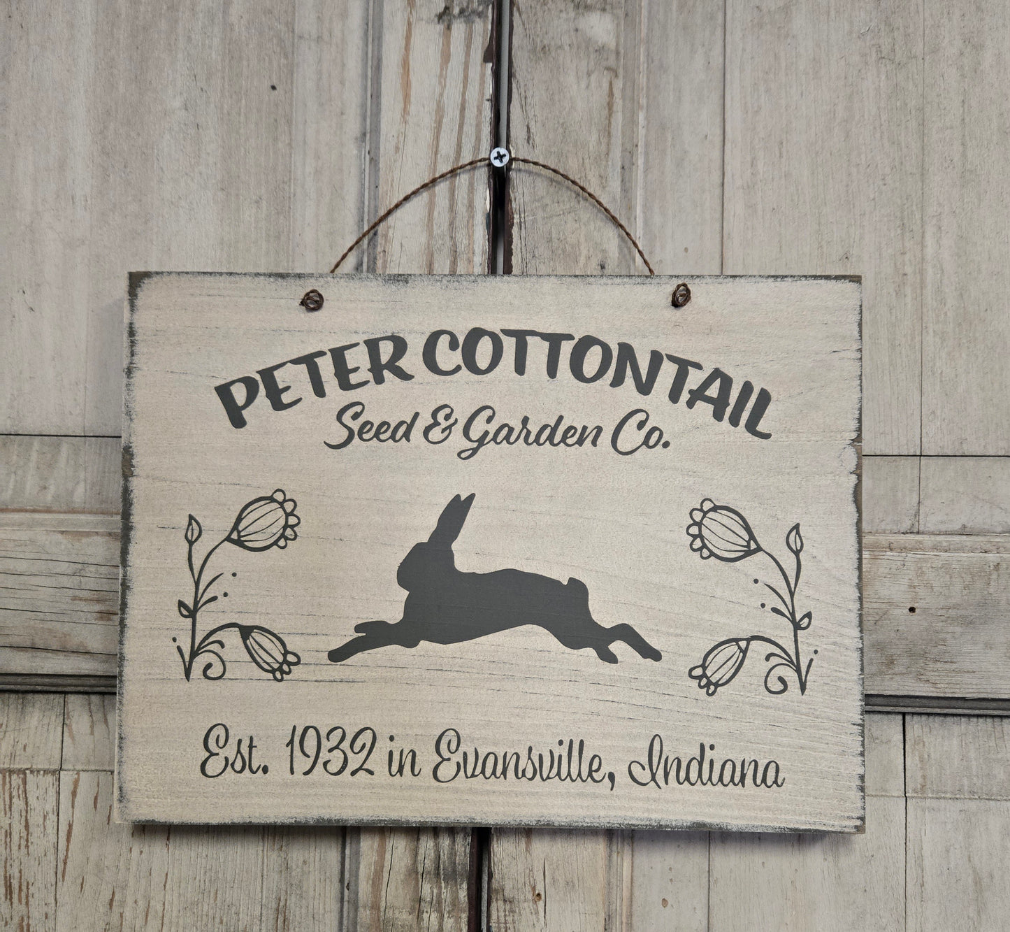 Wooden sign with 'Peter Cottontail Seed & Garden Co.' text and rabbit illustration on a wooden background