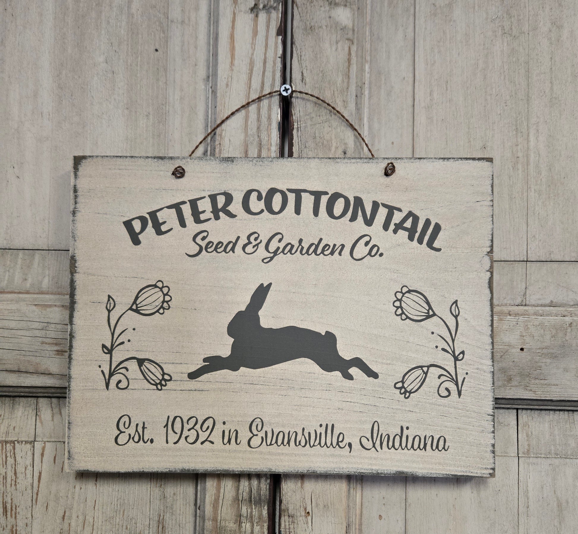 Wooden sign with 'Peter Cottontail Seed & Garden Co.' text and rabbit illustration on a wooden background