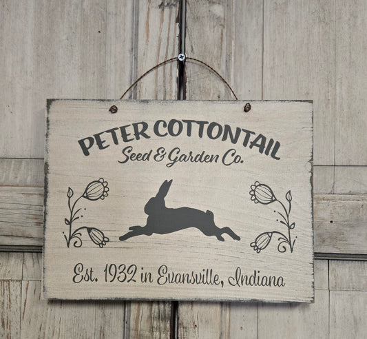 Wooden sign with 'Peter Cottontail Seed & Garden Co.' text and rabbit illustration on a wooden background