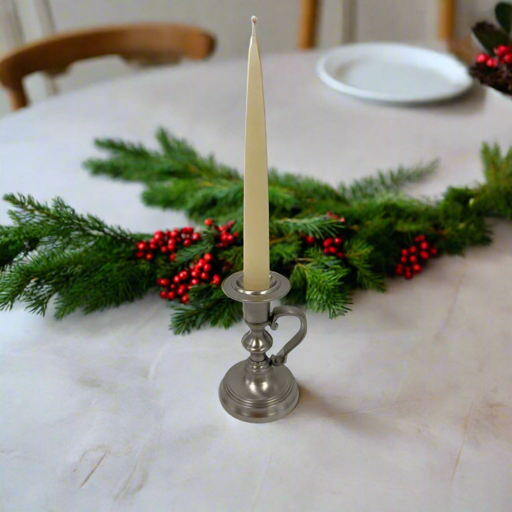 A pewter-plated brass antique reproduction chamberstick with a 4-1/2 inches tall and 3 inches wide base, designed to hold a candle.