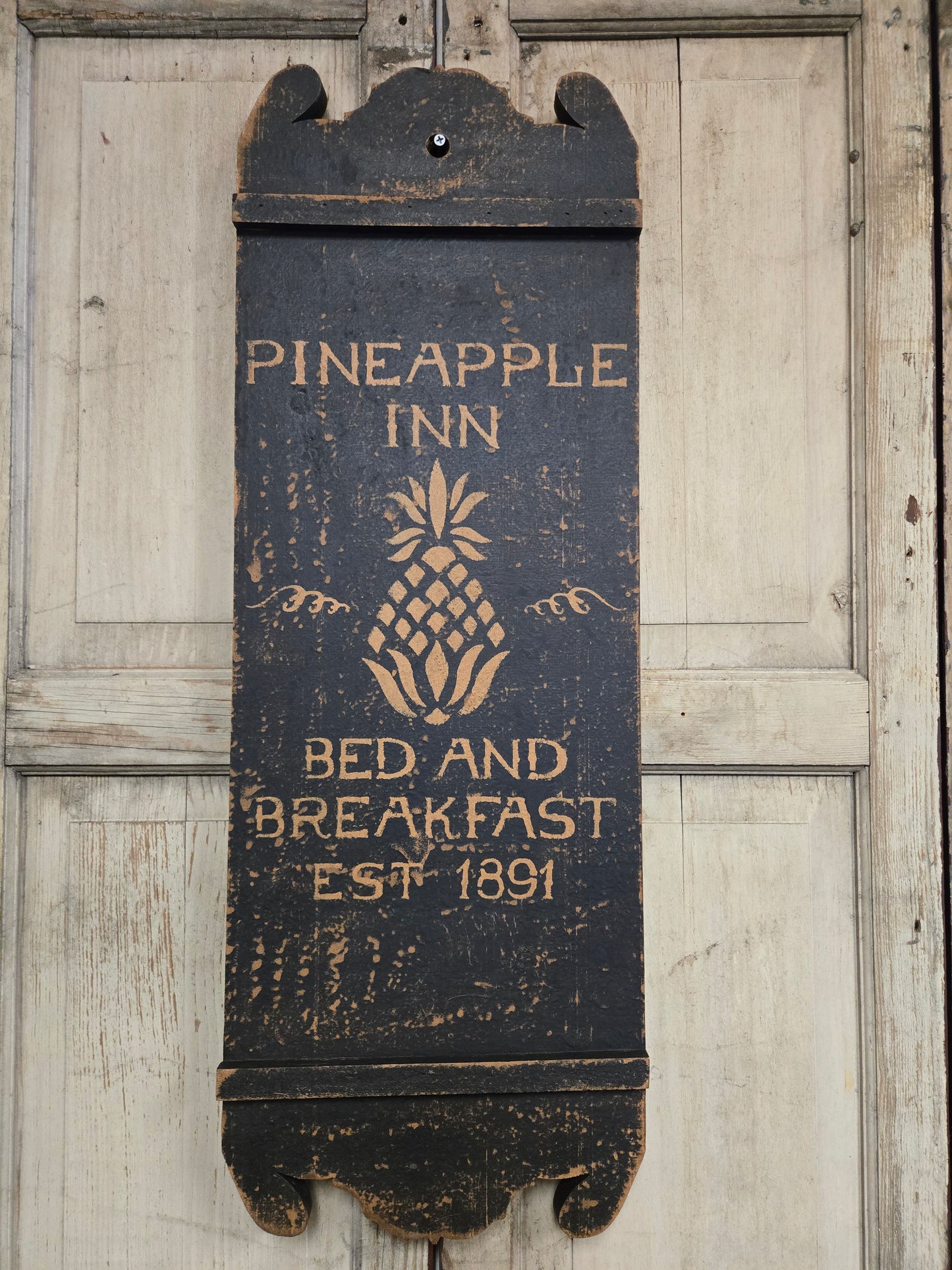 Wooden sign for Pineapple Inn Bed and Breakfast on a wooden background