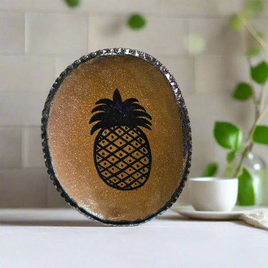 A small oval stoneware plate with a brown glaze and a pineapple motif