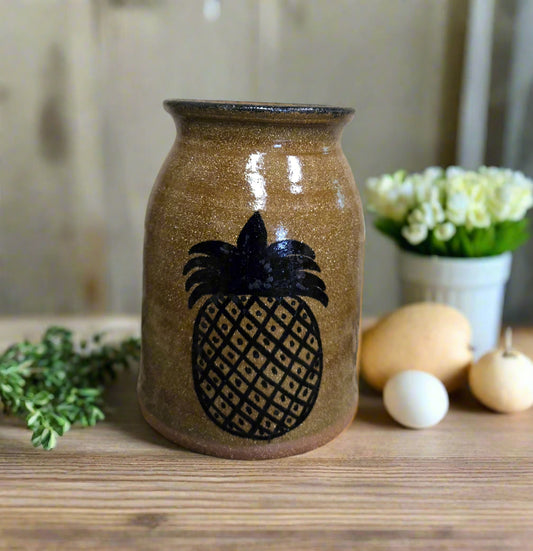 Stoneware canning crock with a pineapple motif against a weathered wood background