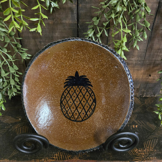 Ceramic bowl with pineapple design on a wooden surface with greenery