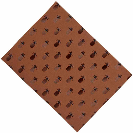 A square brown placemat with a pineapple town pattern.
