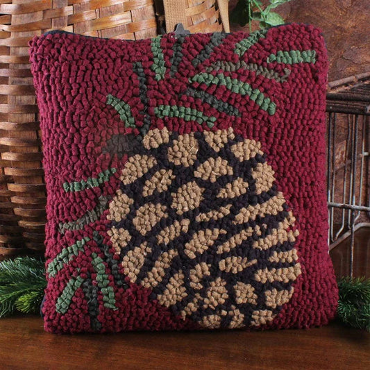 Decorative pillow with a pine cone design on a wooden surface