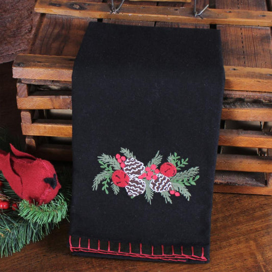 Black towel with embroidered Christmas design on a wooden surface
