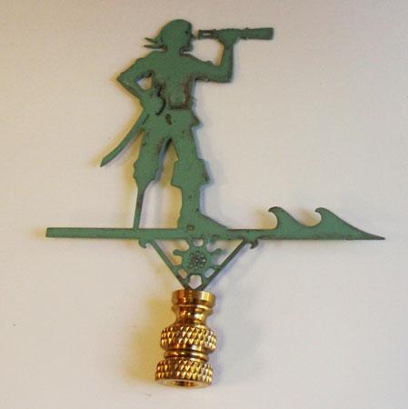 A verdigris lamp finial in the shape of a pirate holding a telescope, with a green patina finish and a gold-colored top.