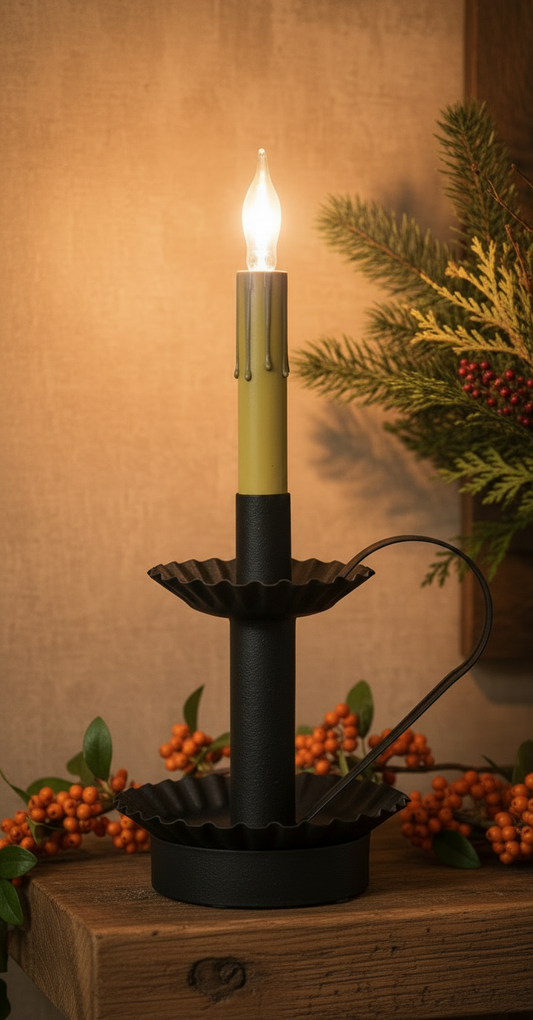 Decorative candle-style light with a black base and gold candle holder, set against a warm-toned background with foliage.