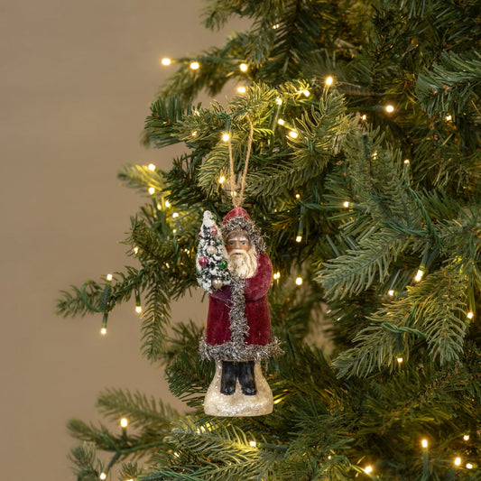 Decorative Christmas ornament of a Santa Claus figure on a lit Christmas tree.