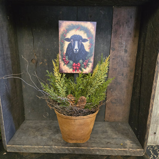 Decorative painting of a black sheep with red berries on a wooden surface with a plant.