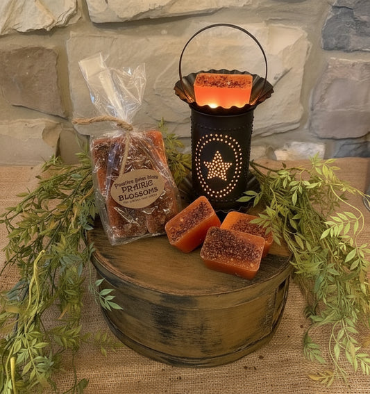 Wax melts with tart warmer on band box against a stone wall.