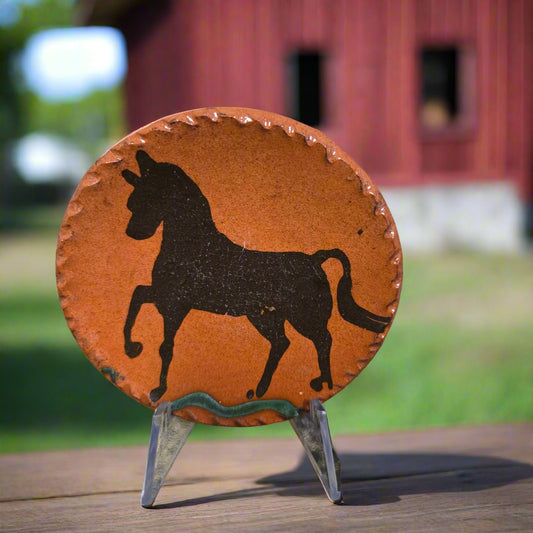 Small round redware plate with a brown prancing horse motif