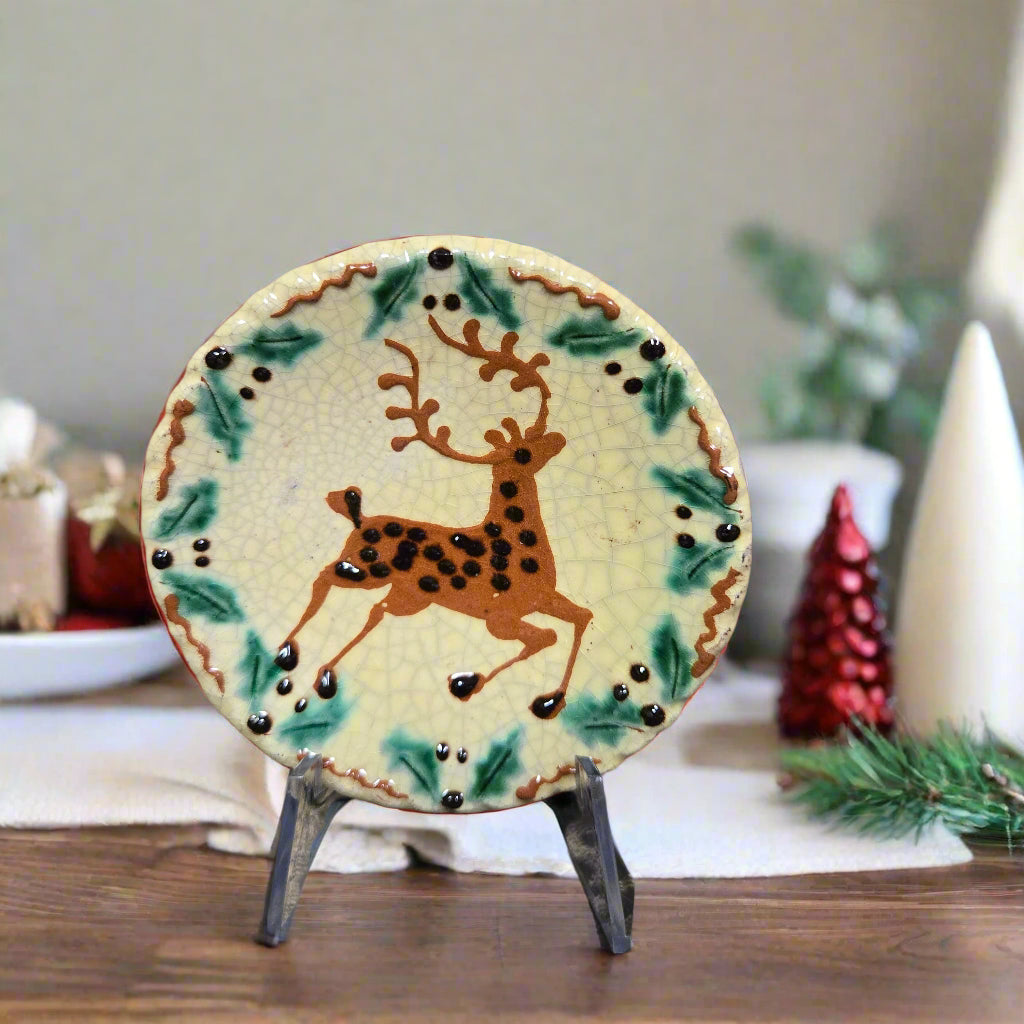 Small round redware plate with a prancing stag and holly border 