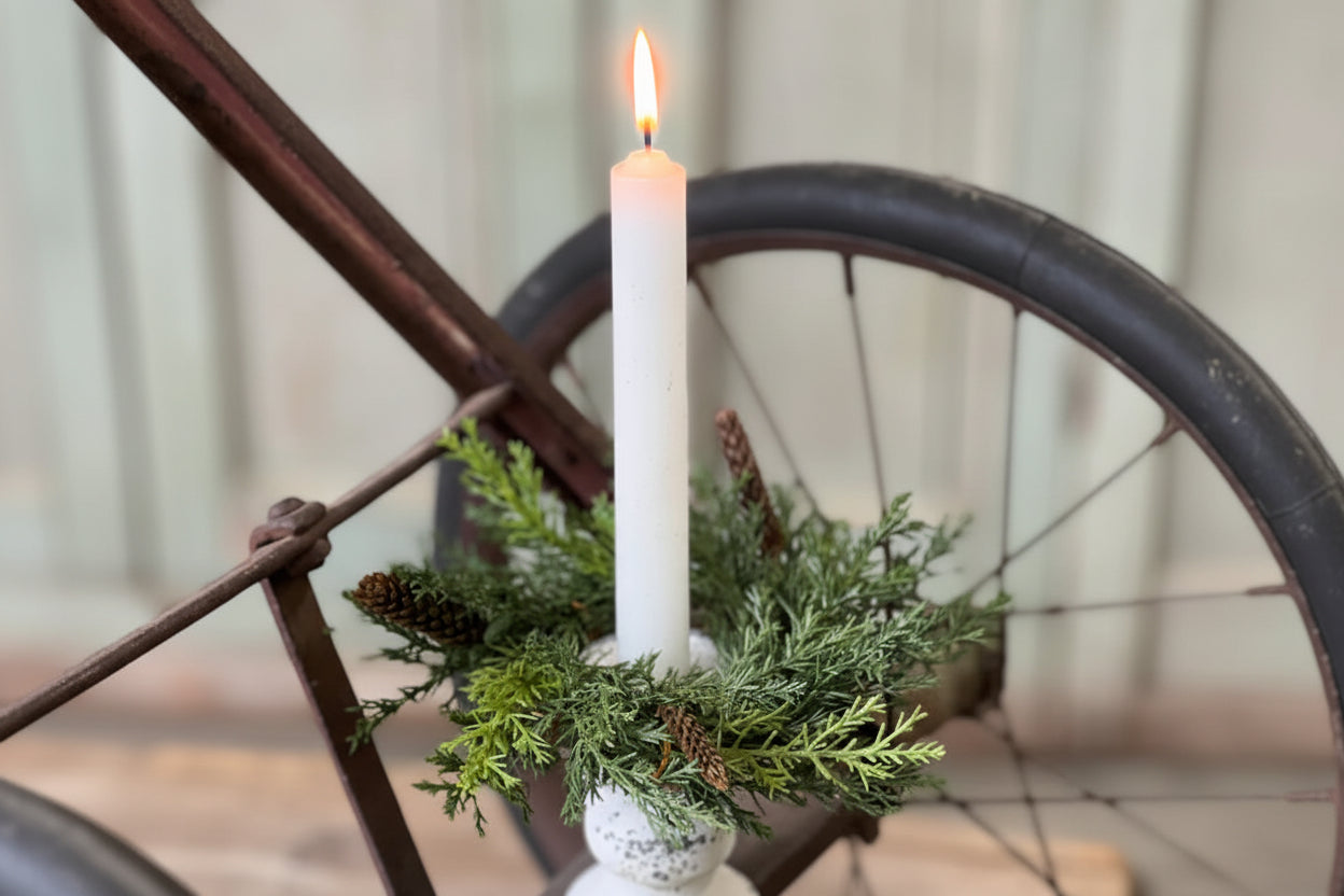 Candle in a decorative holder with greenery on an old bicycle.