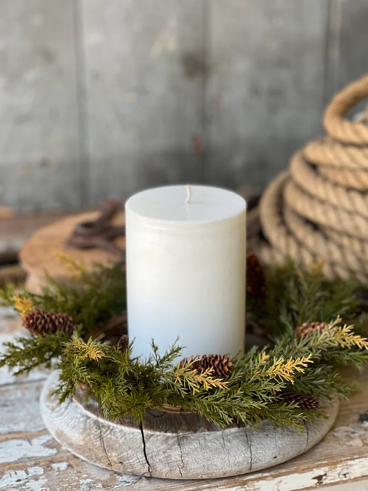 12 inch prickly pine candle ring with pinecones on a white pedestal with pillar candle.