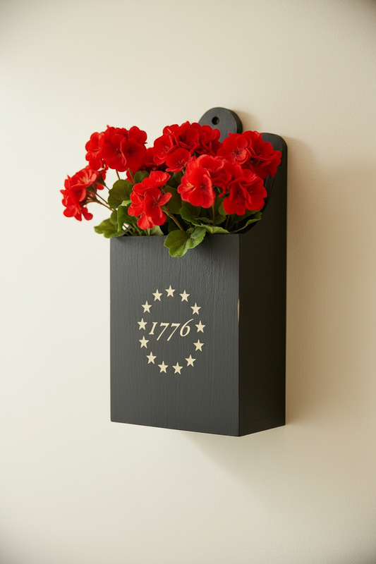 Wall-mounted planter with red flowers and '1776' design on a plain background