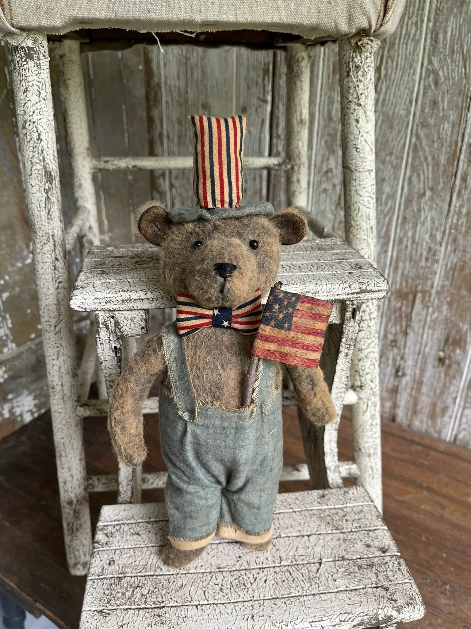 Teddy bear with American flag accessories on a wooden ladder