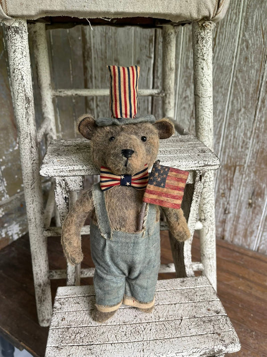 Teddy bear with American flag accessories on a wooden ladder