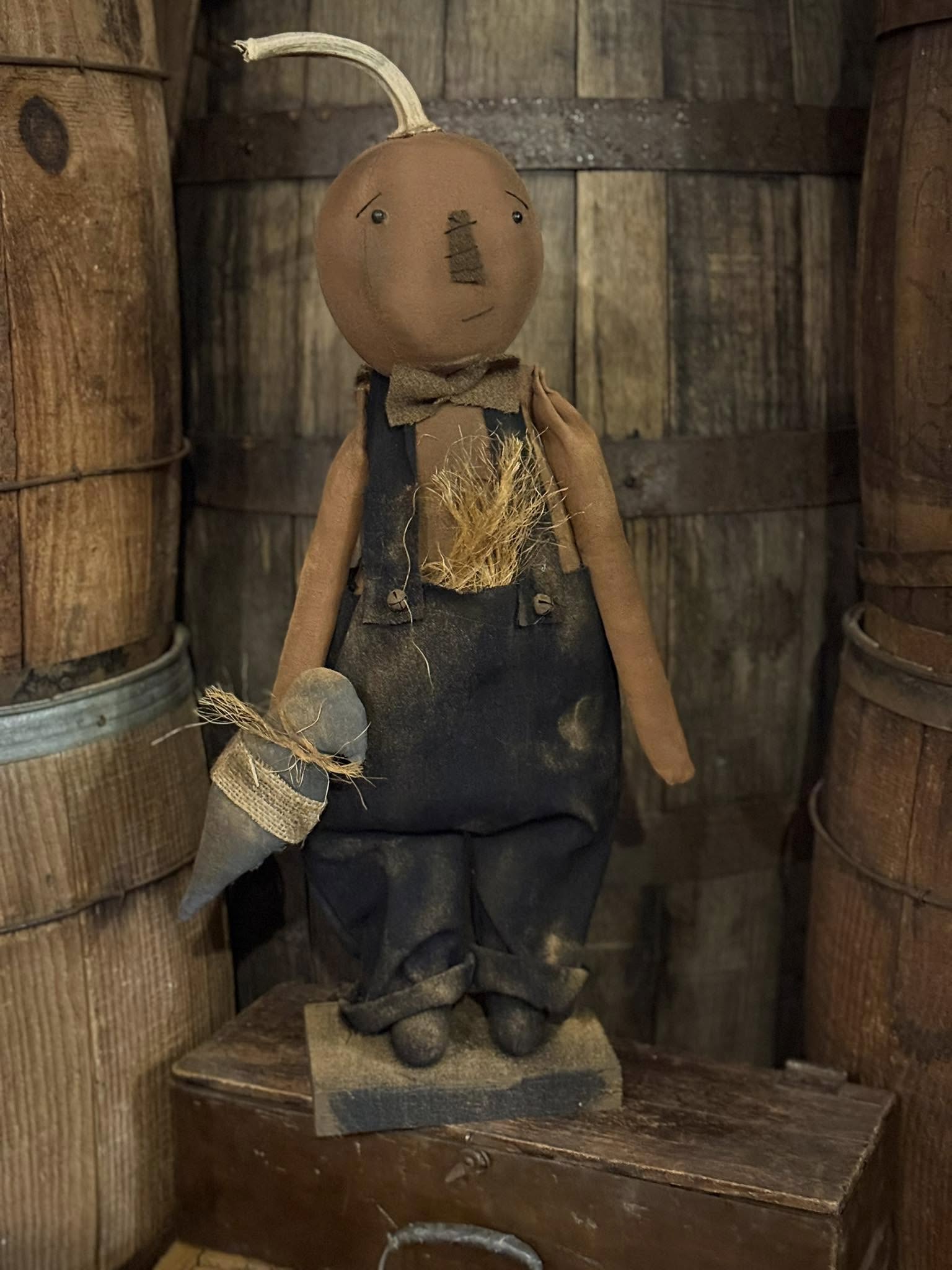 Vintage-style scarecrow figure in a rustic setting with wooden barrels.