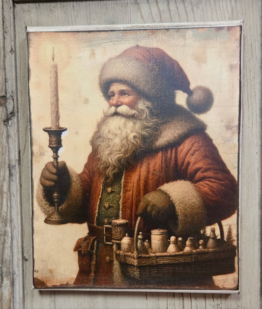 A canvas print depicting a traditional image of Santa Claus holding a candlestick, with a basket of toys in front.