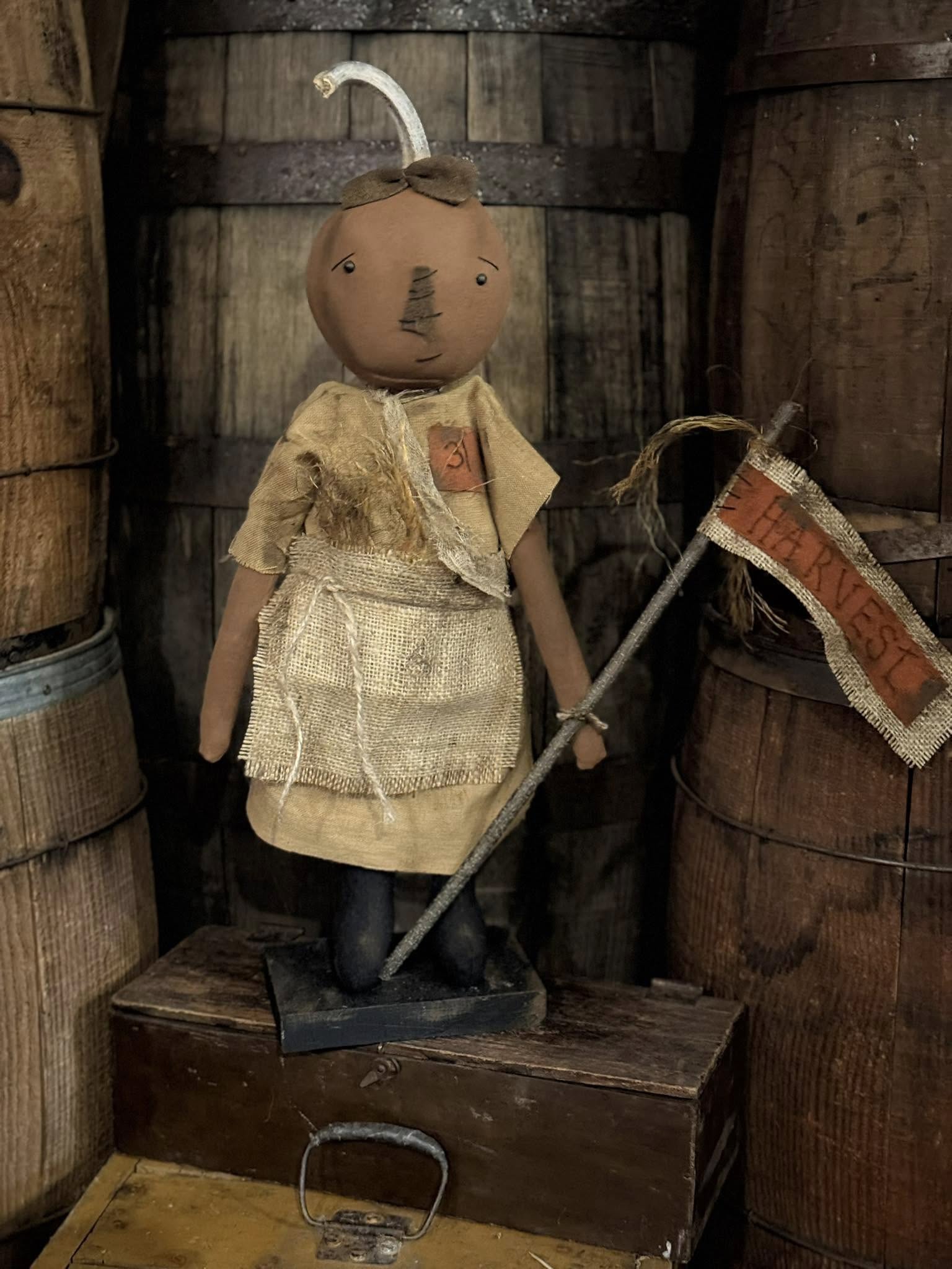 Vintage-style doll with a flag and lantern in a rustic wooden setting