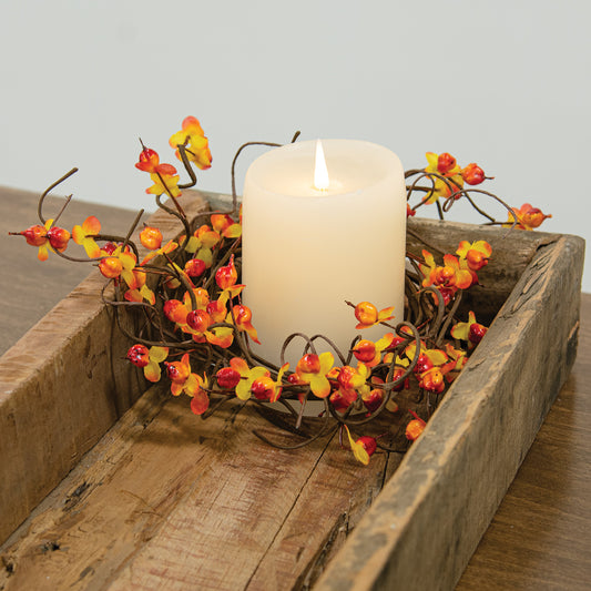 Candle in a wooden box with decorative branches on a wooden surface
