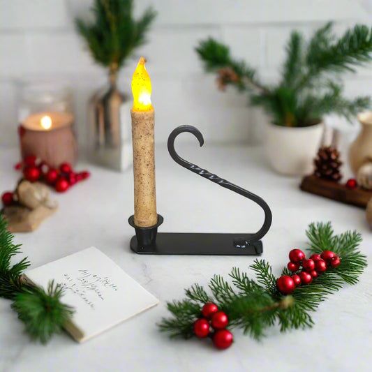 Decorative candle holder with a lit candle on a table with Christmas decorations.