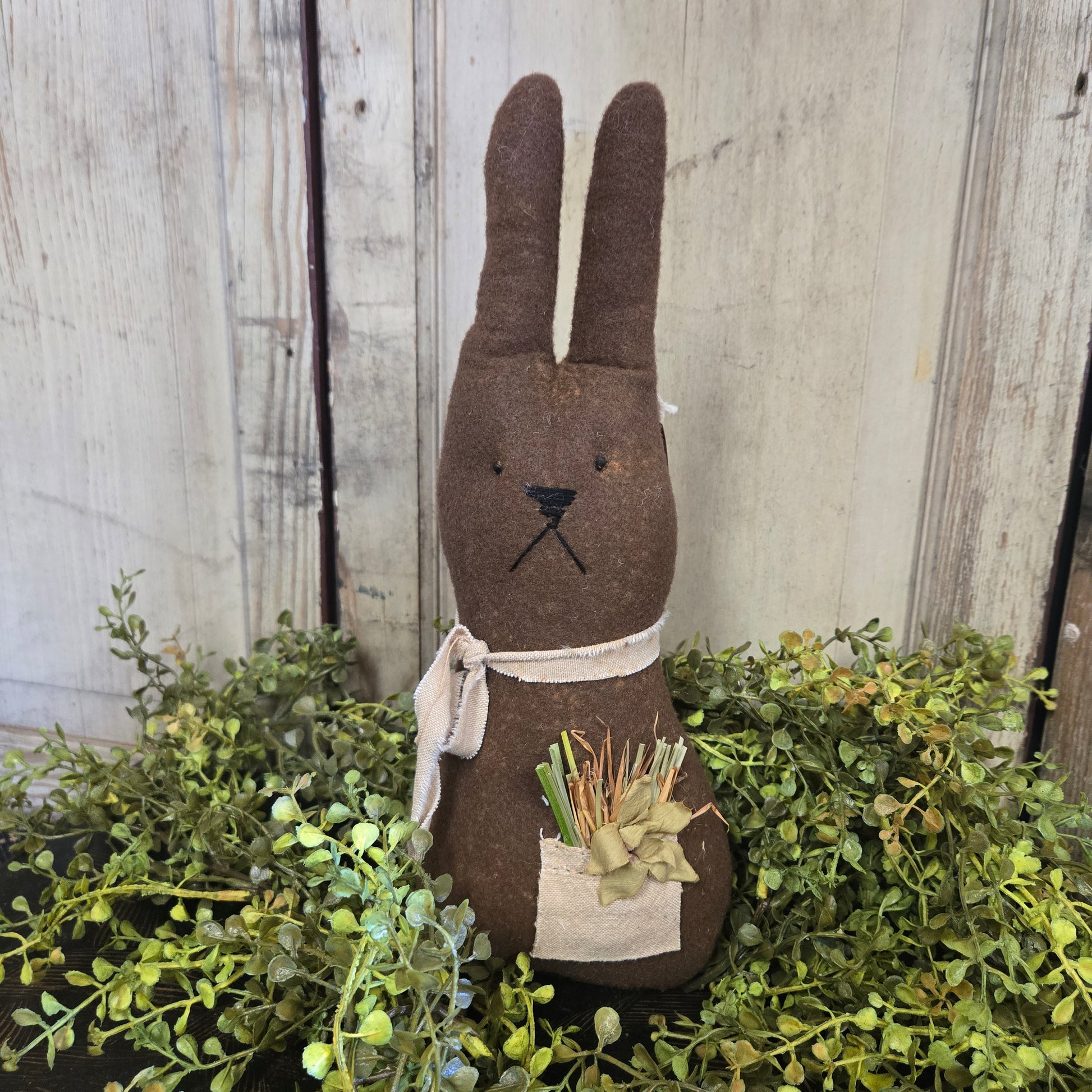 Decorative rabbit figure with greenery on a wooden surface