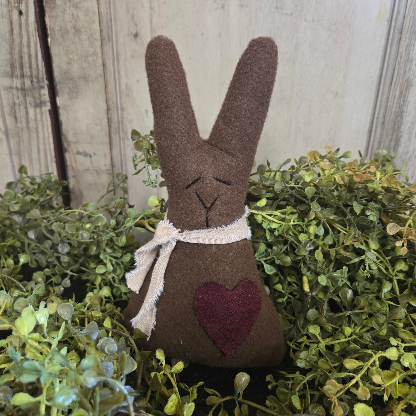 Decorative brown bunny with a heart on a green leafy background