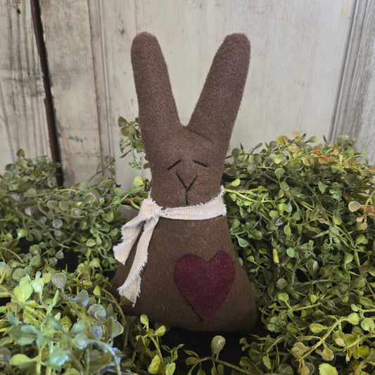 Decorative brown bunny with a heart on a green leafy background