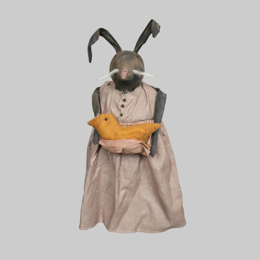 Bunny wearing a long dress with a chick against a wooden wall.