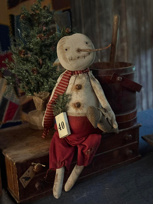 Vintage-style snowman figurine with a red scarf and hat, standing on a wooden surface with a rustic background.