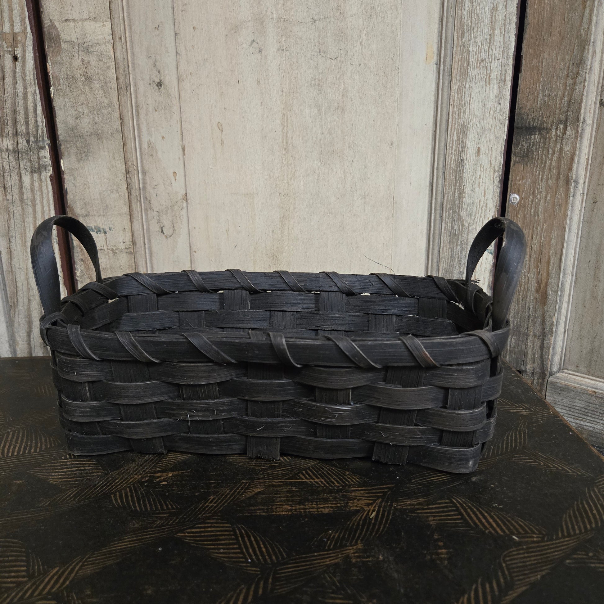 Woven black basket on a wooden surface