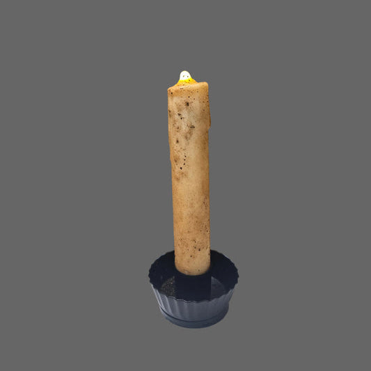 Primitive nubby battery operated taper in black candle holder on gray background.