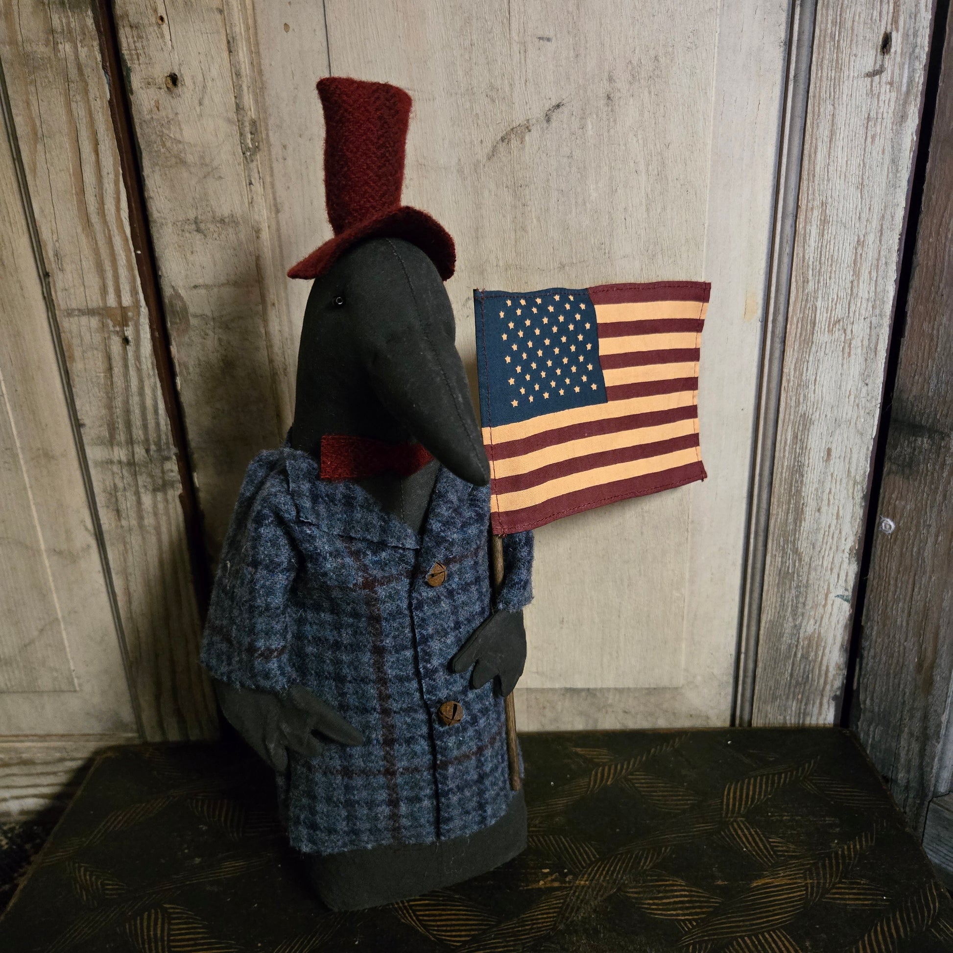 Primitive crow wearing a suit with an American flag on a wooden surface