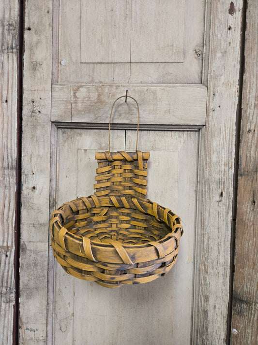A handmade primitive cupboard basket with a rustic mustard color, displayed against a wooden background.